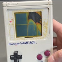 a person is holding up a nintendo game boy